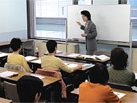 松本玲子先生がホワイトボードの前で説明している教室の全体写真
